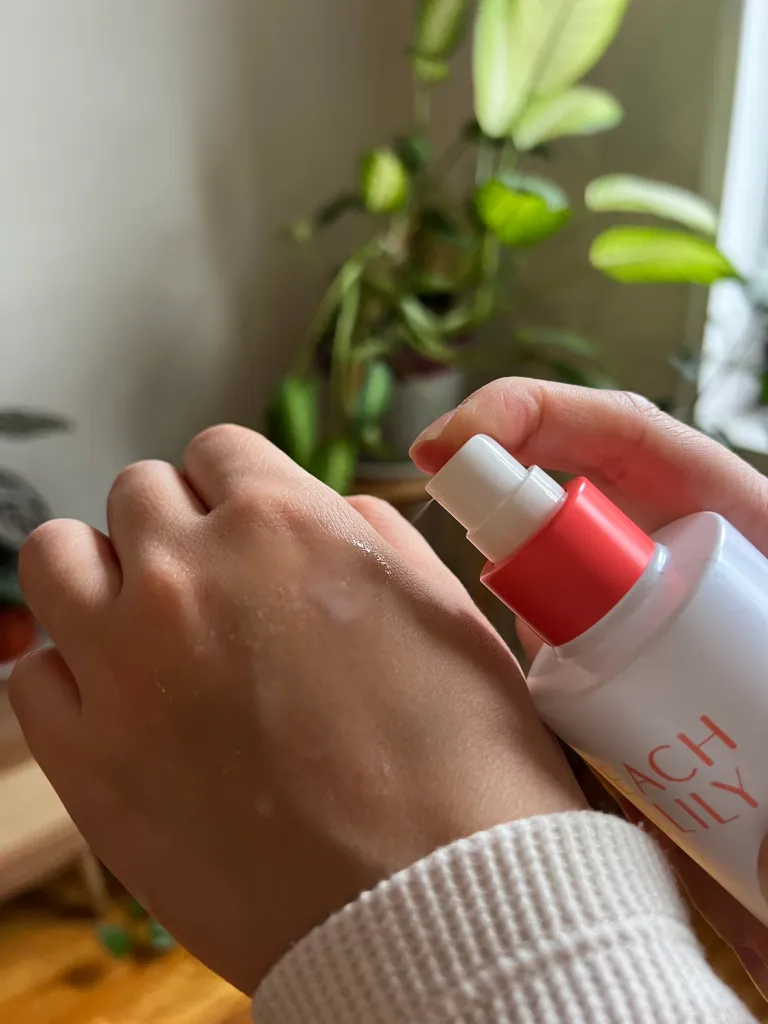 Woman spraying hydrating mist on back of hand