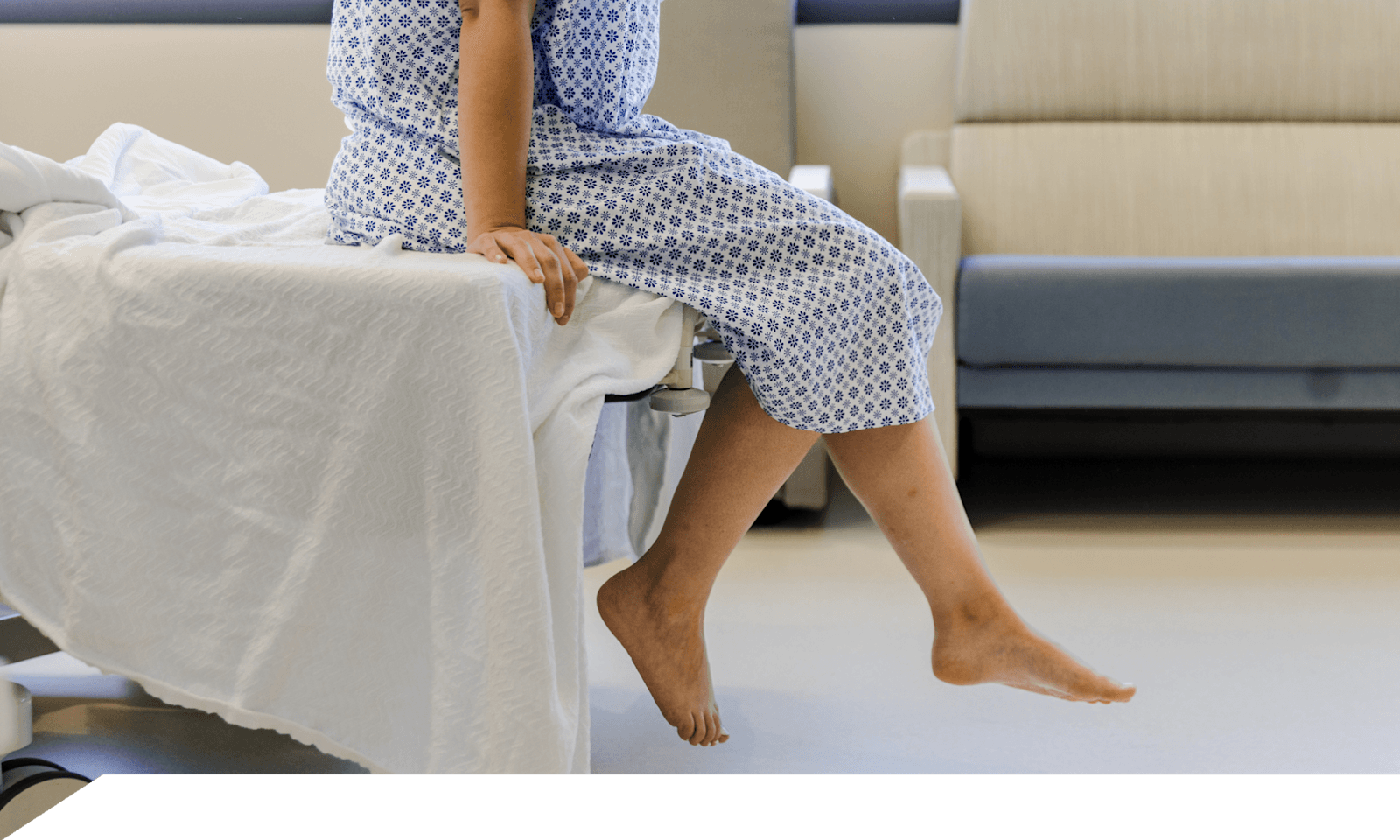 A woman sitting on a hospital table wearing a gown