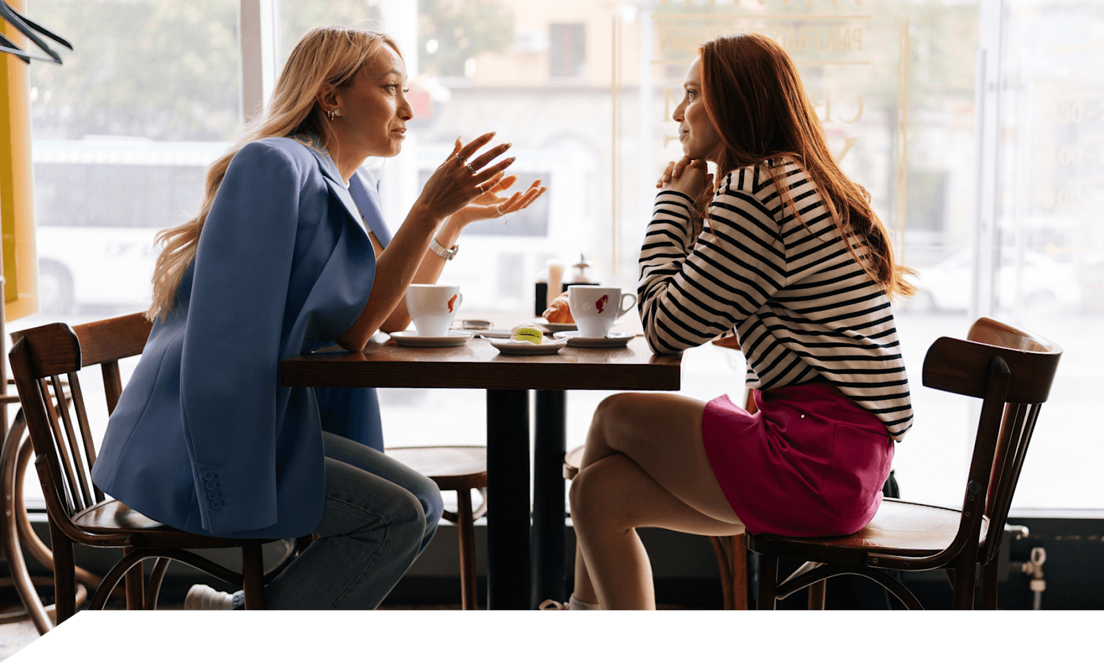 Two women talking, sitting at a coffee shop