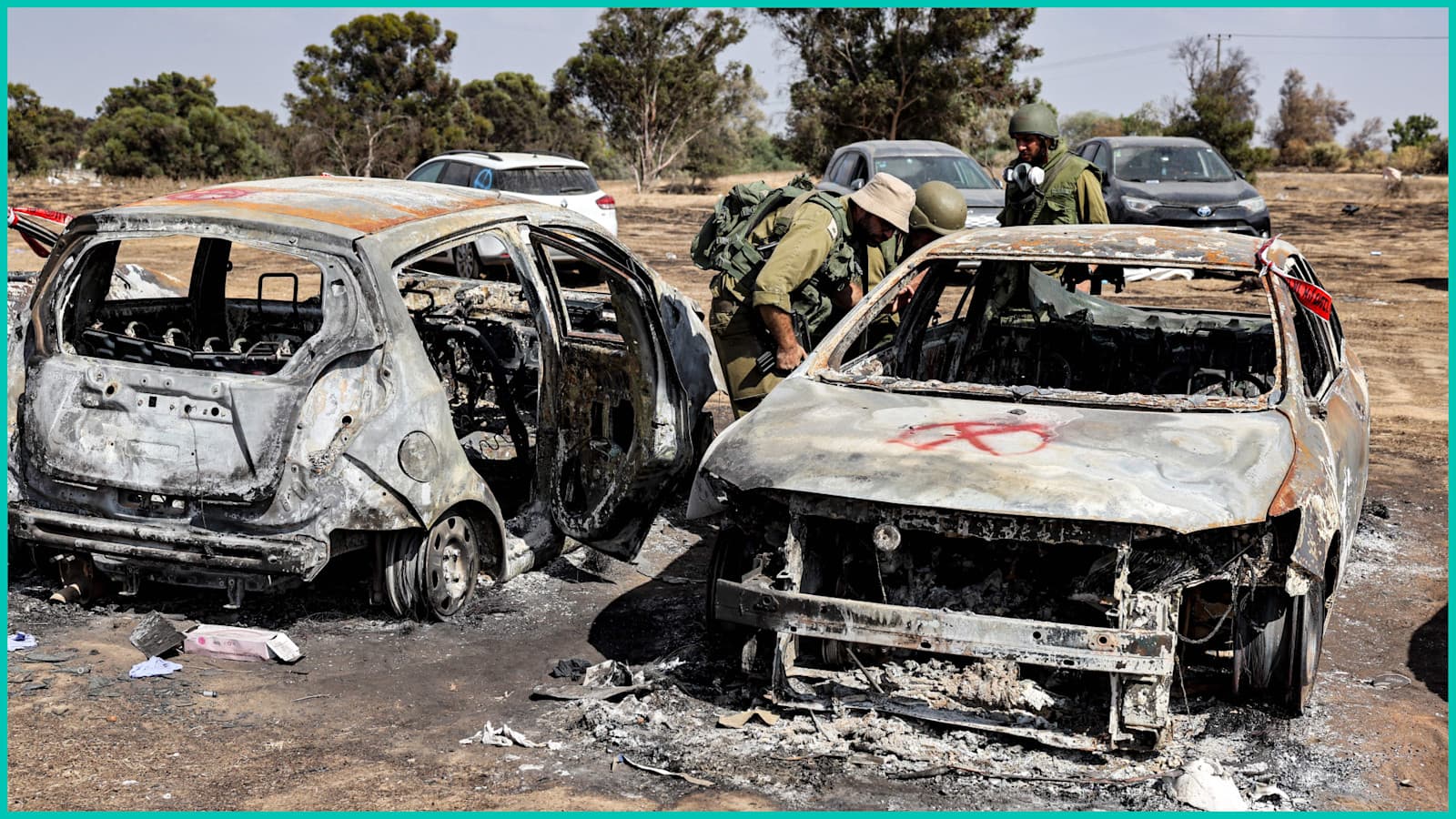 Israeli soldiers near a kibbutz in southern Israel search vehicles torched by Hamas during its  Oct. 7, 2023 attack on Israel.