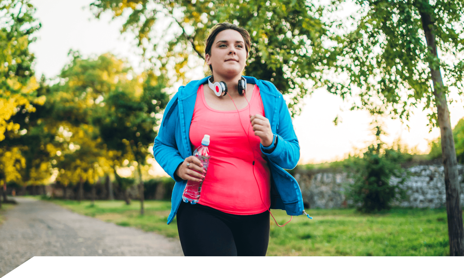 A woman walking in a park wearing workout clothes
