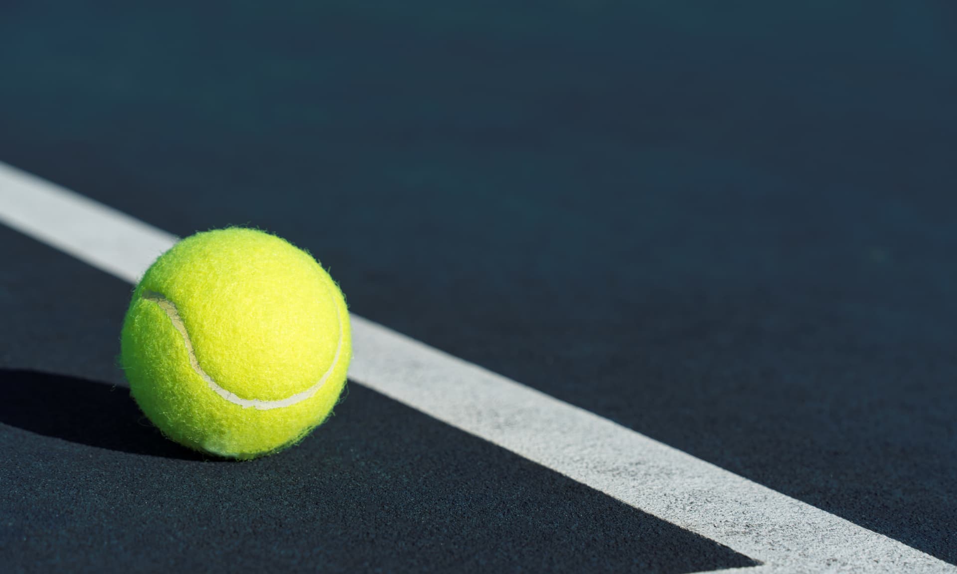 A close up of a tennis ball near the court's boundary line