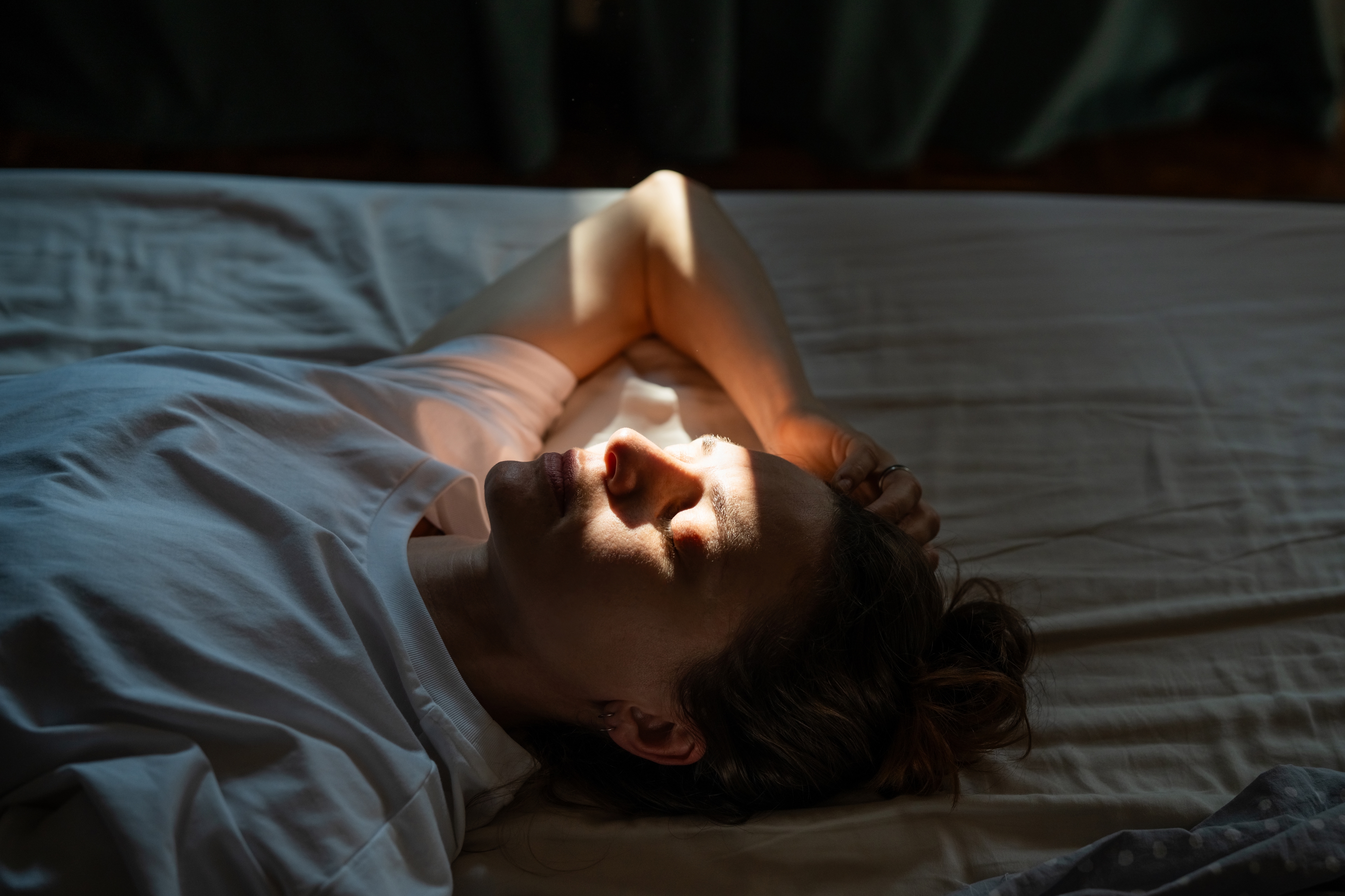 Woman laying on bed unable to sleep because of perimenopause