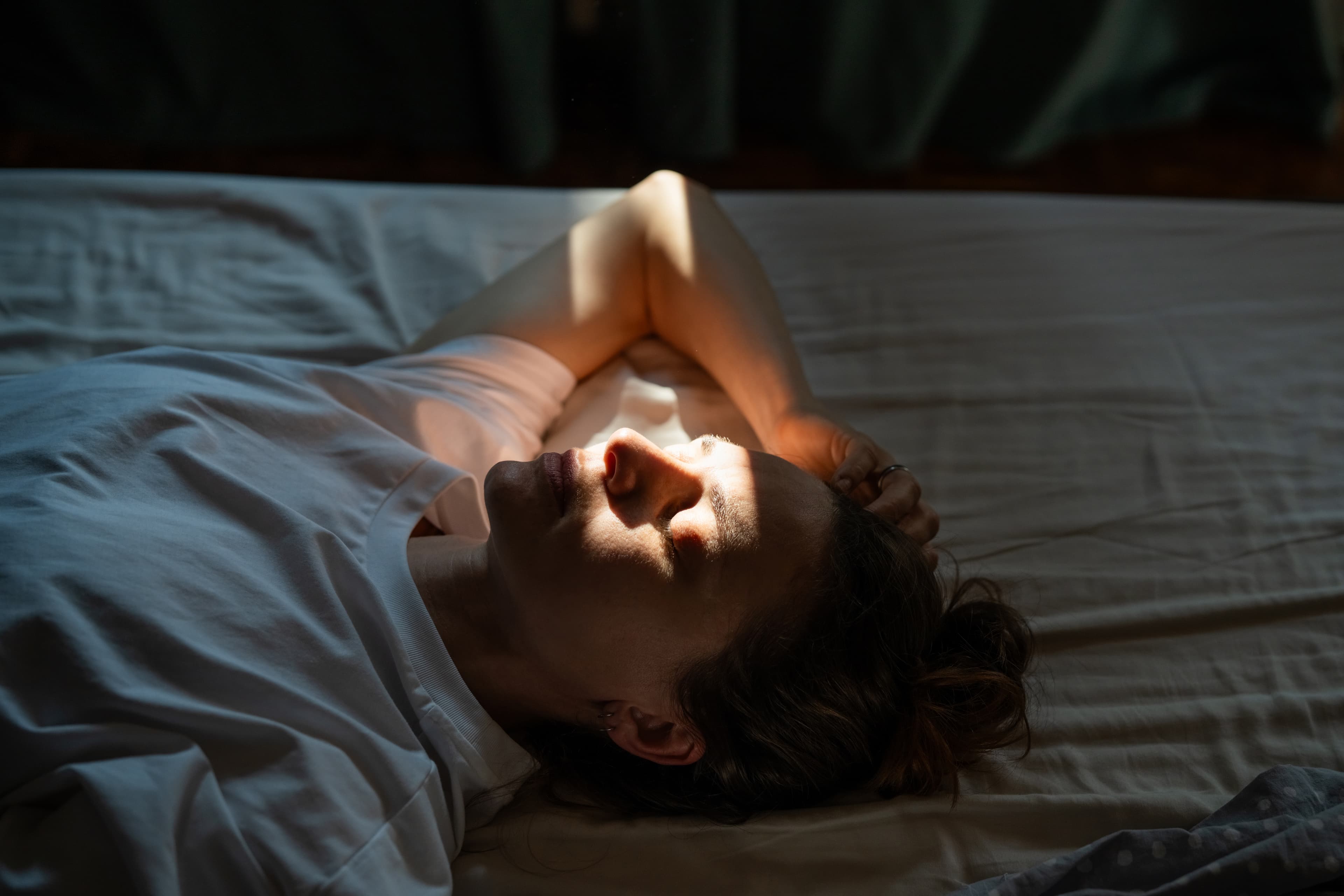Woman laying on bed unable to sleep because of perimenopause