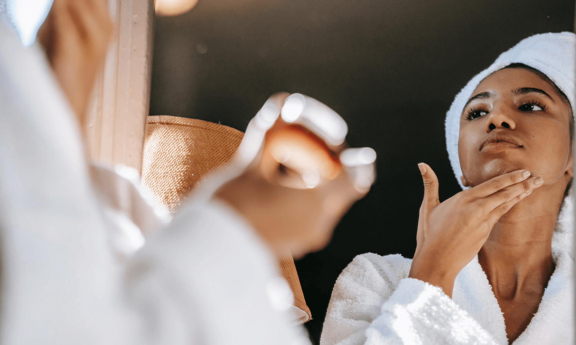 A woman applying moisturizer in the mirror