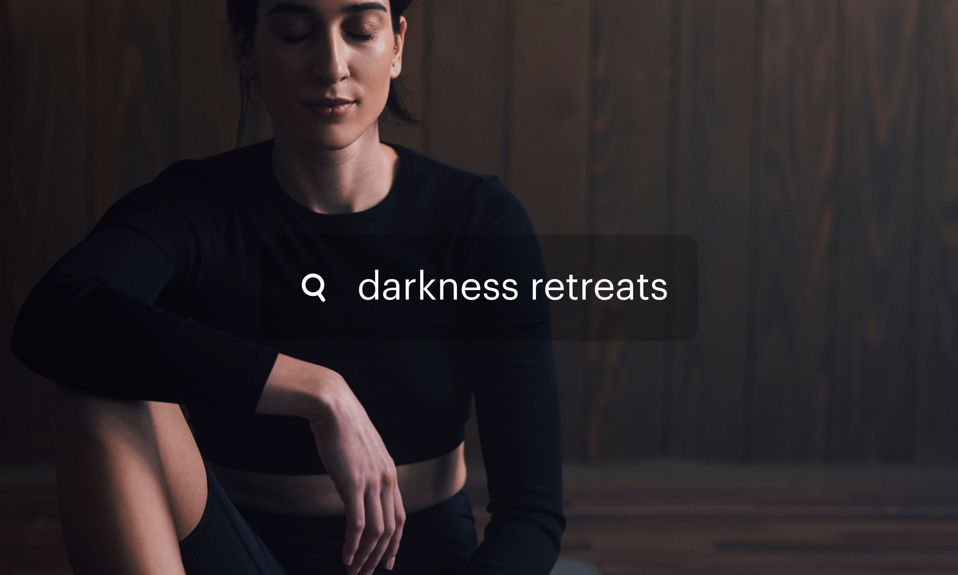 A woman sitting in a dark room with her eyes closed