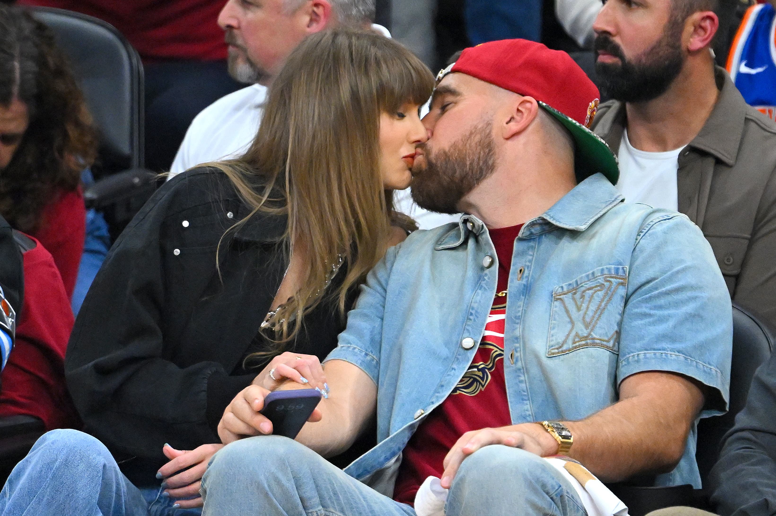 Taylor Swift and Travis Kelce of the Kansas City Chiefs kiss during Game Three between the New York Knicks and the Cleveland Cavaliers.