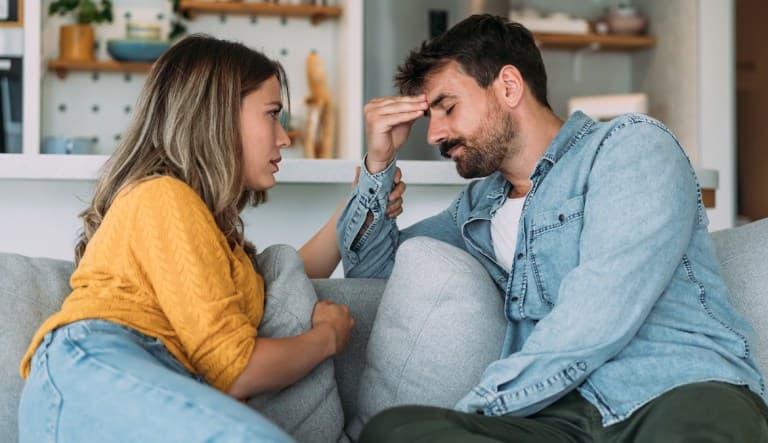 A photo of a young wife expressing empathy and compassion to her sad frustrated husband. This photo is being used to promote an article addressing the topic