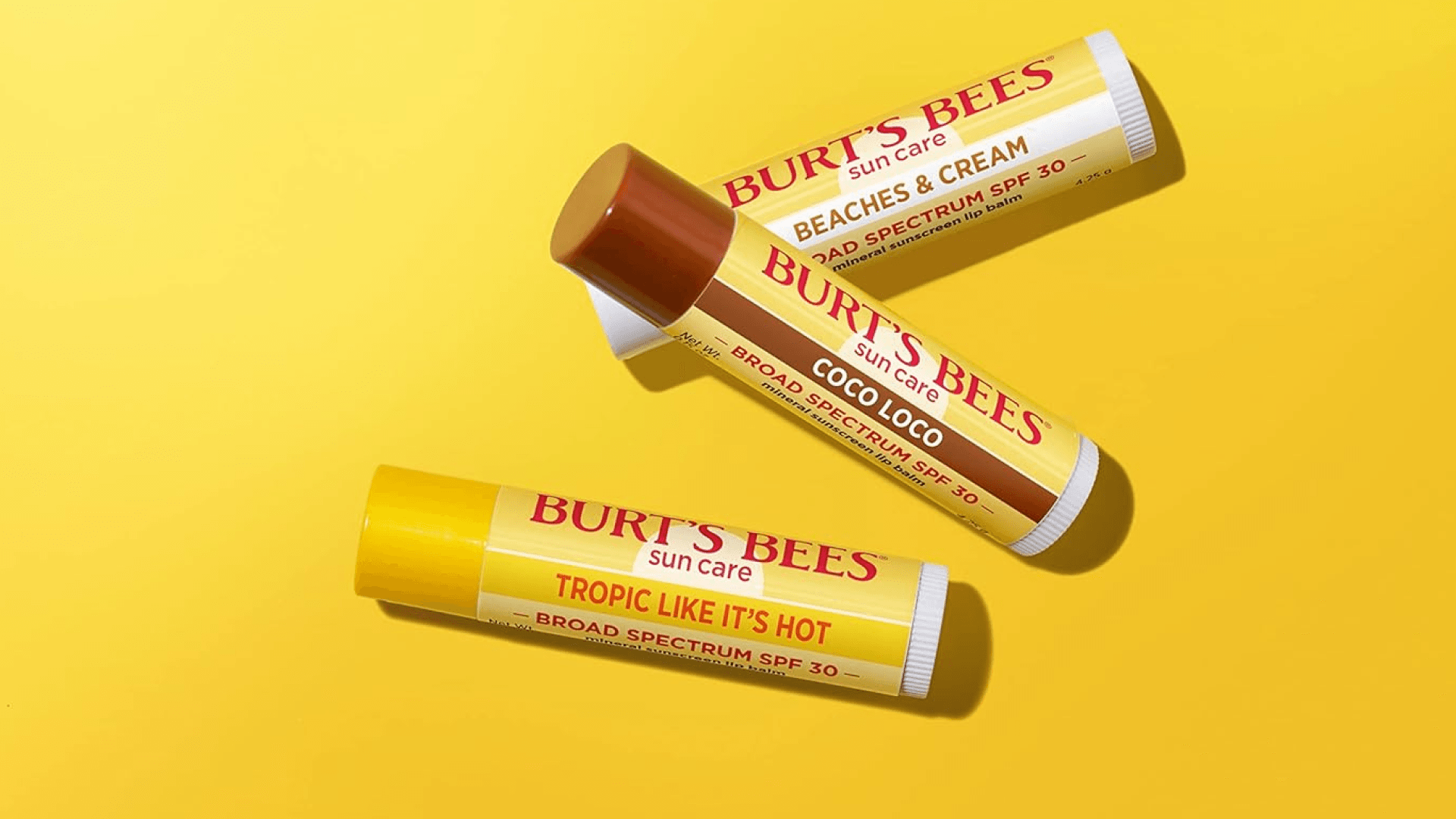 Three tubes of chapstick on a yellow background