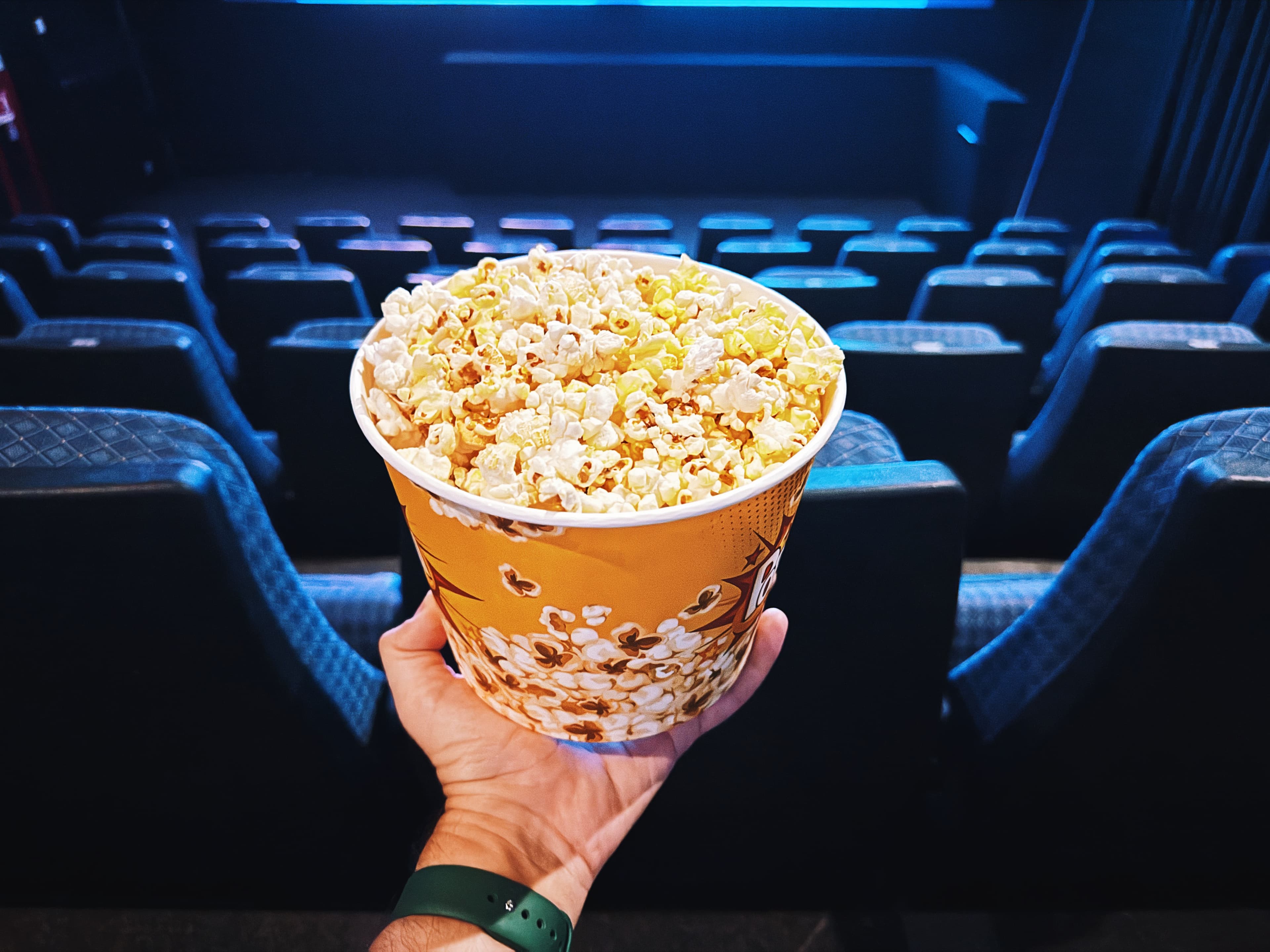 Stock photo of a person holding popcorn at a movie theater