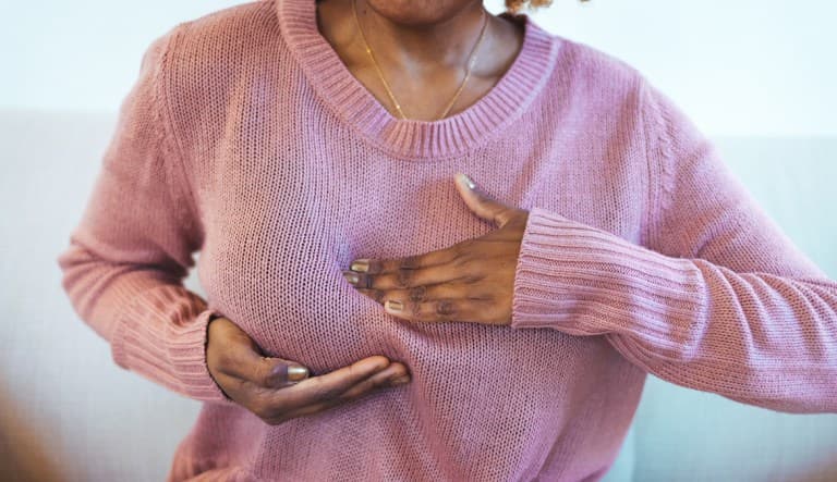 A woman feels her breast through a sweater to check for breast cancer. This photo is being used in an article about sad nipple syndrome.